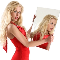 Beautiful girl in red clothes looks in a mirror