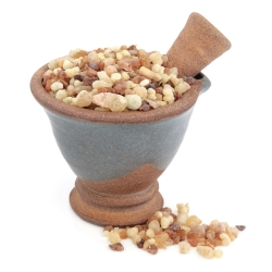 Frankincense and myrrh in a mortar with pestle over white background.