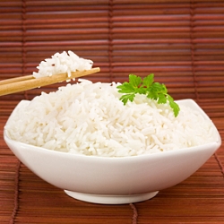 Closeup of rice on chopsticks and a bowl on mat